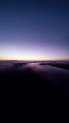 Poster - A blurry image of a cloudy sky with a purple hue. The sky is filled with clouds and the sun is setting