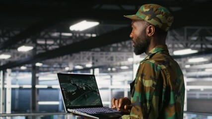 Poster - Soldier in server room uses geospatial data to support evacuation during emergency operations. Military data center personnel in uniform coordinating disaster response logistics using laptop, camera B