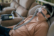 © littlepigpower - Man wearing cpap machine while lying in electric massage chair