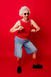 © VISTA by Westend61 - Energetic woman dancing in front of a red background wearing sunglasses and a red top