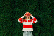 © VISTA by Westend61 - Woman in a striped shirt holding a tomato and bell pepper outdoors in front of arborvitae