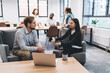 © BullRun - Two coworkers having in-depth one-on-one conversation in modern lounge zone, discussing business goals while team works in background, highlighting collaboration and mentoring culture