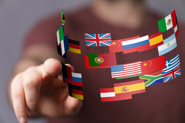 Fototapete - Hand interacting with a digital display of flags representing global connections and international business.