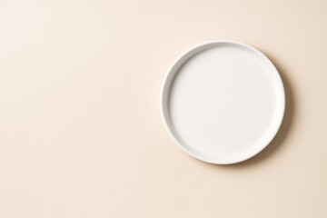Poster - Minimal white round plate on beige background with copy space for branding or food mockup and design concepts.