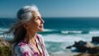 © O - Senior woman with gray hair smiling joyfully overlooking the ocean. Happy retirement and mindful living concept. Positive aging.