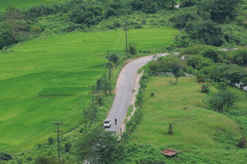 Wall Mural - A panoramic summer landscape of rolling green hills, a winding river, and distant mountains under a vast sky