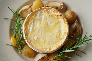 Poster - A round pastry filled with cheese, topped with herbs, surrounded by roasted potatoes and sprigs of rosemary.