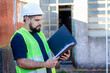 © South Pixels - Portrait of male factory or industry worker wearing safety gear holding a folder or a binder outdoor.Recycle factory concept.Construction site.