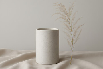 Poster - Serene Ceramic Vessel: A minimalist ceramic vessel, both functional and decorative, sits elegantly besides dried ornamental grass, on draped, light fabric with a soft focus.