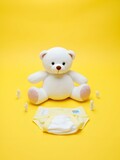 Baby diapers and teddy on yellow color floor