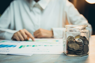 Poster - Concept of saving money. Detailed Analysis of Business Growth with Coins in Glass Jar on Wooden Table at Night