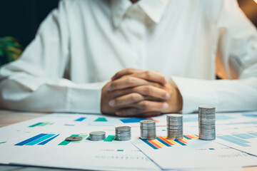 Poster - concept of saving money. business person analyzing financial data with coins on desk and charts show