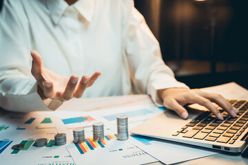 Poster - Concept of saving money. Business Professional Analyzing Financial Reports with Laptop and Coins on Table in Modern Office Environment