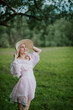 © Hrvoje - Graceful woman in pink dress and straw hat in a serene meadow