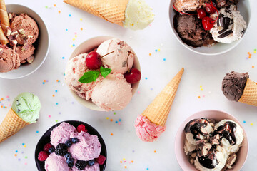 Poster - Summer ice cream table scene. Bowls and cones of colorful assorted flavors. Top view on a white marble background.
