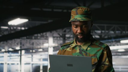 Poster - Army information technology specialist in data center troubleshooting military computer systems and networks using laptop. Soldier in command center server room using notebook, camera B