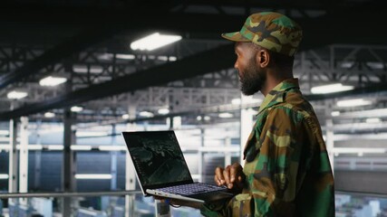 Poster - Military technician in data center monitoring warfare drone telemetry on laptop dashboard. IT specialist in army server room using tactical interface on notebook to support aerial operations, camera B