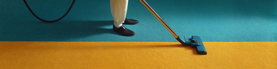 Poster - A person vacuuming a carpet with blue and yellow sections wearing black shoes and white pants legs