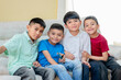 © Stock Latino - Four hispanic kids sitting on sofa smiling and relaxing