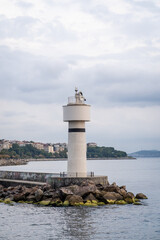 Aufkleber - Bosphorus lighthouse standing tall against the coastal skyline on a cloudy afternoon with calm waters and rocky shore