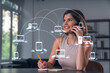 © VideoFlow - Smiling businesswoman in casual wear holding using smartphone typing at office workplace with notebook. Concept of distant work, business education. Social network icons chain hologram