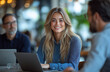 © Muhammad - Collaborative Office Meeting – Woman Smiling While Working on Laptop with Colleagues in a Modern Open-Space Workplace with Bright, Minimalist Interior Design