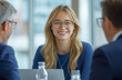 © Muhammad - Collaborative Office Meeting – Woman Smiling While Working on Laptop with Colleagues in a Modern Open-Space Workplace with Bright, Minimalist Interior Design