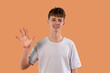 © Iryna - Young person smiling and waving or showing number five 5 against  brown background