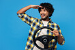 © ViDi Studio - Young happy Indian man he wear yellow checkered shirt casual clothes hold steering wheel driving car look far away distance isolated on plain blue cyan background studio portrait. Lifestyle concept.