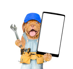 Poster - Funny Mastiff puppy wearing blue cap and denim overalls with tool belt showing big smartphone with white blank screen in it paw. Isolated on white background