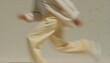© RaptorWoman - Blurred image capturing the dynamic motion of a person running in beige clothing against a neutral background.