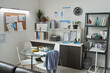 © pressmaster - Well-organized medical office featuring a table with cups and snacks, cabinets filled with folders, and a bulletin board with various documents