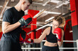 © New Africa - Woman in protective gloves having boxing practice with her coach at training center