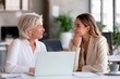 © Віталій Б. - Two women are having an engaging conversation at a bright, modern office. They seem to be discussing ideas while sitting at a table with a laptop and paperwork