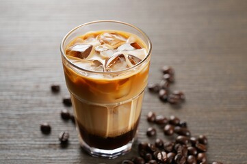 Poster - A glass of iced coffee with ice cubes and a sprinkle of cinnamon on the table.