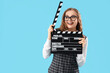 © Pixel-Shot - Beautiful actress with movie clapper on blue background