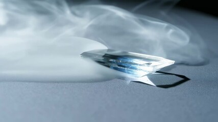 Poster - White smoke gracefully swirling around translucent topaz crystal, highlighting mineral's elegant transparency against stark gray surface and dramatic black background
