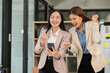 © Thitisak - Two Asian businesswomen happily express their joy at the office.