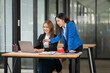 © Thitisak - Two Asian businesswomen using laptops, on the table there are graph documents working on business investment.