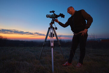 Wall Mural - amateur astronomer using telescope and smartphone for watching stars, moon, planets and other celest