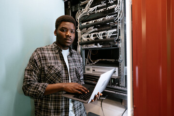 Poster - Young technician working on network server in data center during afternoon