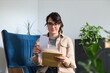 © Andrii Zastrozhnov - Young caucasian female reading mail in cozy living room with plants