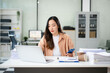 © Nuttapong punna - Asian woman with a smile standing holding notepad and tablet at the modern office..