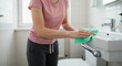 © Vyatcheslav - Woman cleaning sink with cloth in modern bathroom during the day