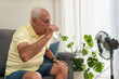 © Renata Hamuda - Senior man refreshing himself drinking water and using an electric fan during a hot summer at home