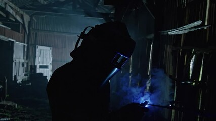 Poster - Welding shadow silhouette helmet sparks industrial dramatic dark worker metal construction safety blue light protective gear