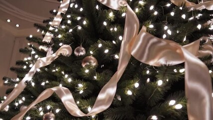 Poster - Elegant holiday living room with Christmas tree, white ribbon, glowing lights, and silver ornaments, creating cozy and festive