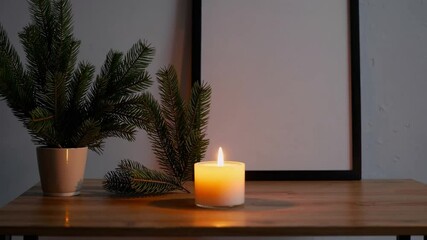Poster - Cozy holiday decor with candle and pine branch on wooden table, peaceful minimalist atmosphere for warm home