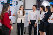 © Wasana - A group of people are standing around a white board with a woman in the middle