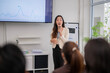 © Wasana - A woman is giving a presentation in front of a group of people